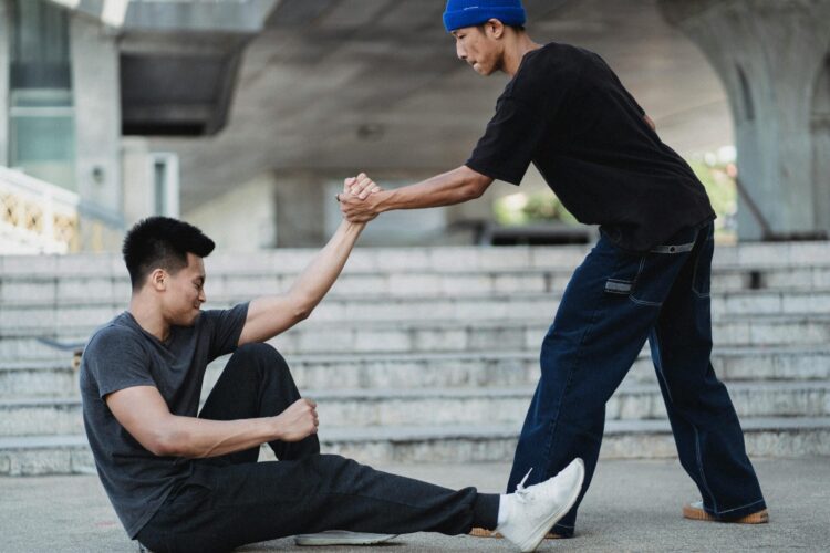 Man helping friend to get up off the ground