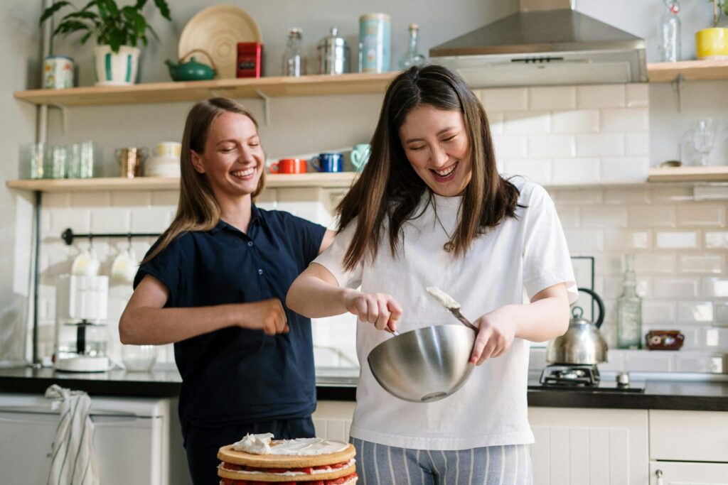 Two women baking a cake laughing