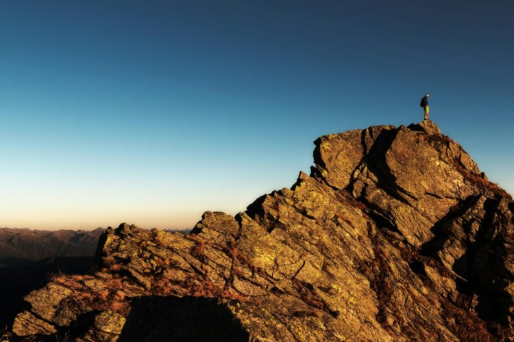 Man standing on top of the rock at day time