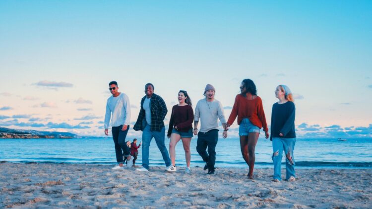 group of friends walking on beach shore