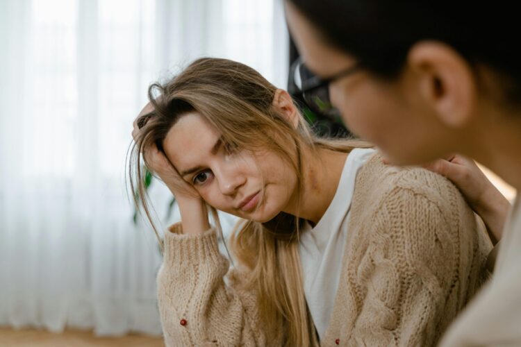 Person patting the stressed woman on her shoulder