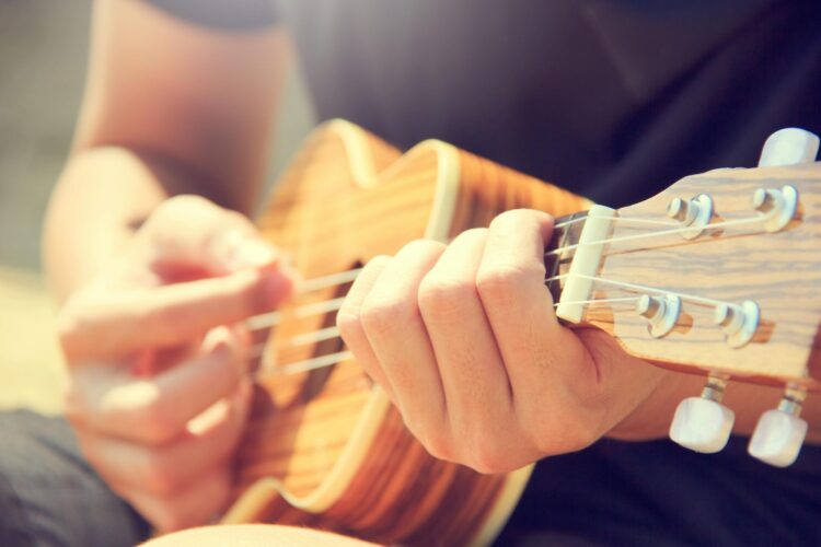 Person playing brown ukulele