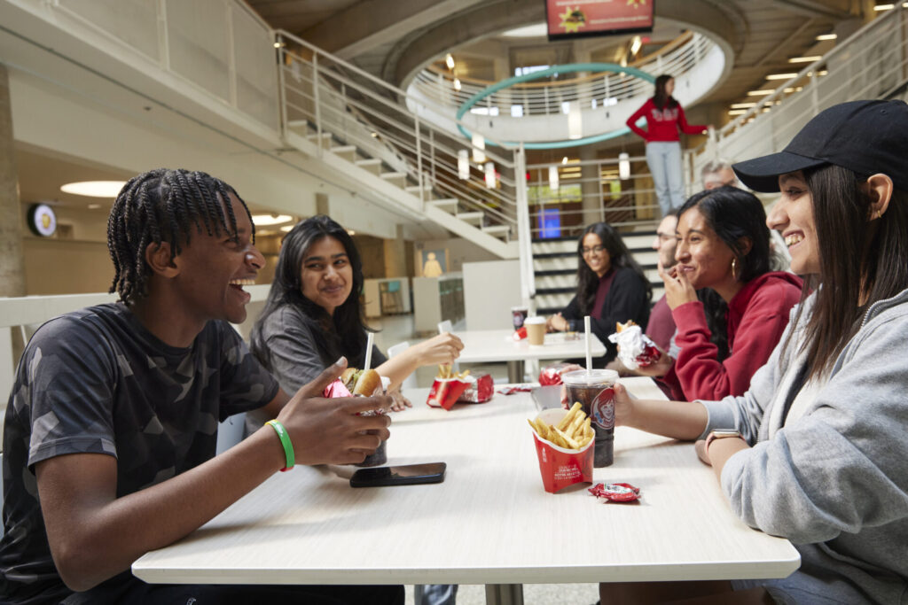 Students sitting in food court eating and laughing