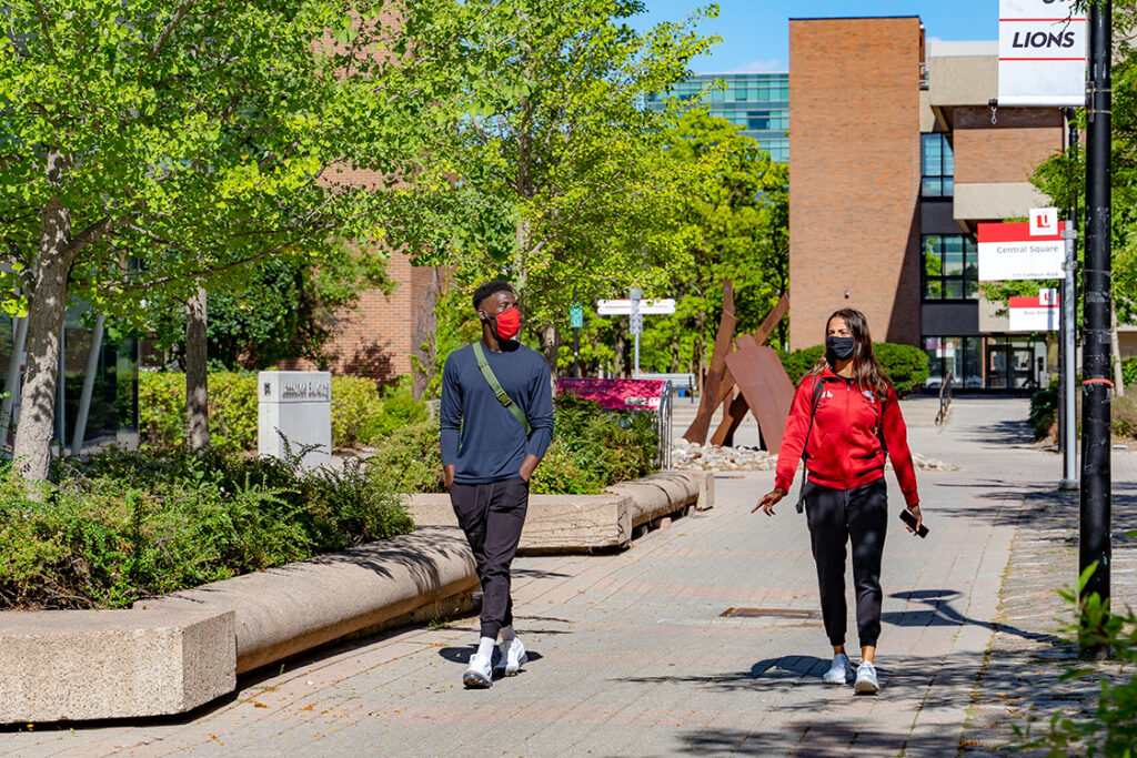 Two students walking on campus with masks on