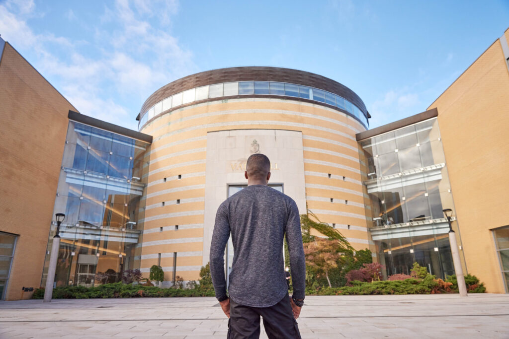 Person standing and facing the front of a building