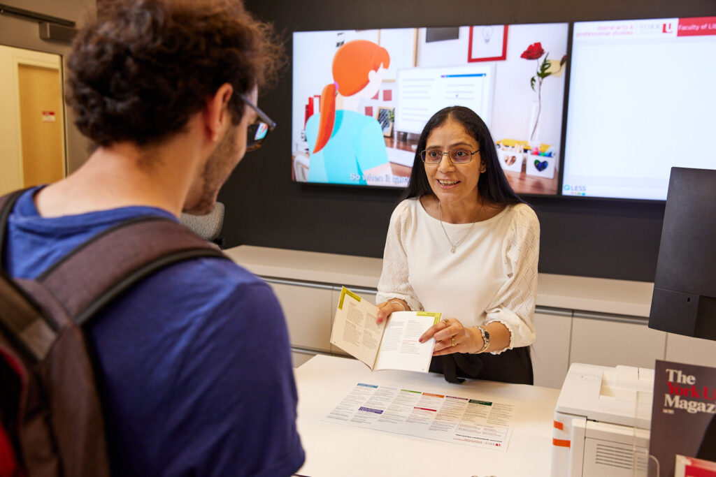 Staff assisting student at a help desk