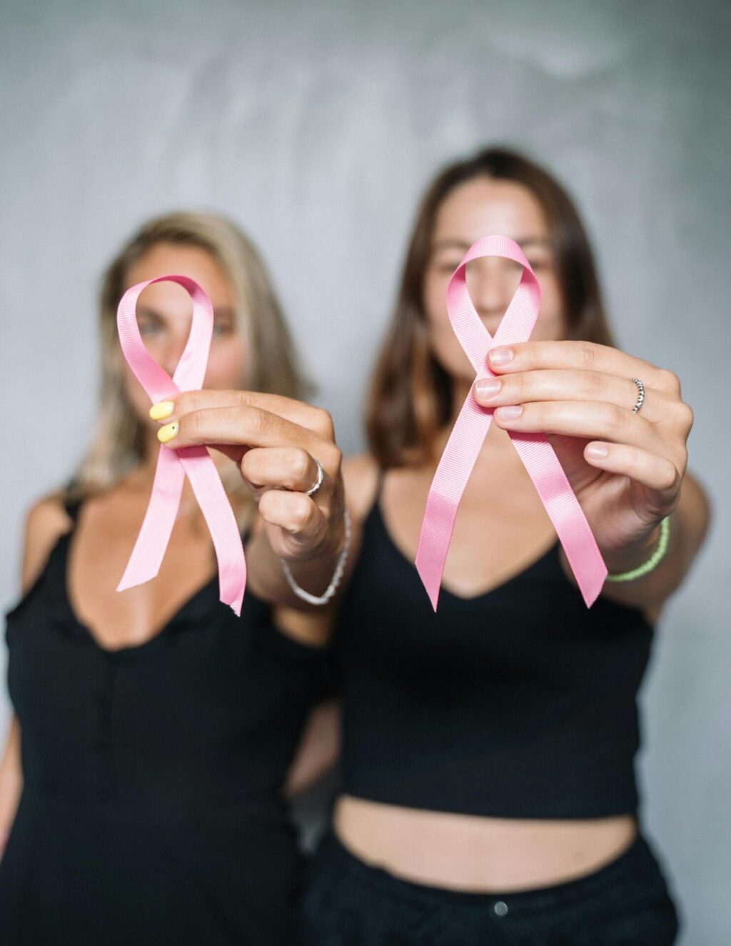 Two women holding up pink ribbons