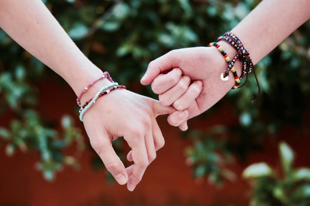 Two people holding hands by the pinky finger