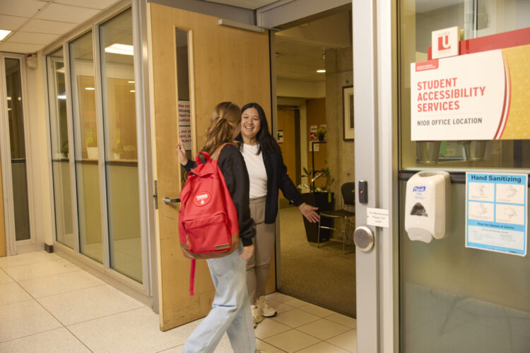 Staff holding door for student walking into Student Accessibility Services office