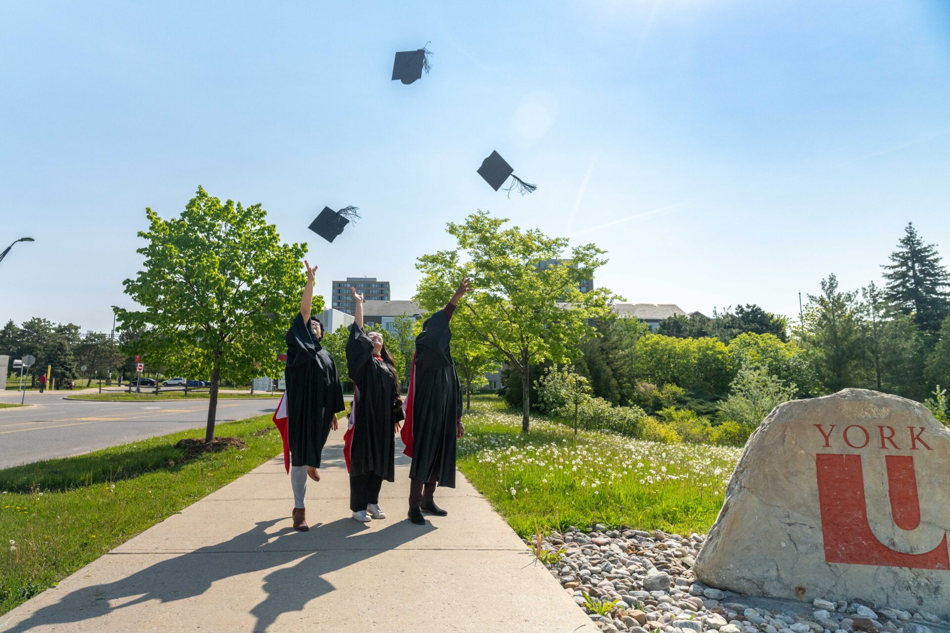 Three students tossing graduation hats in the air