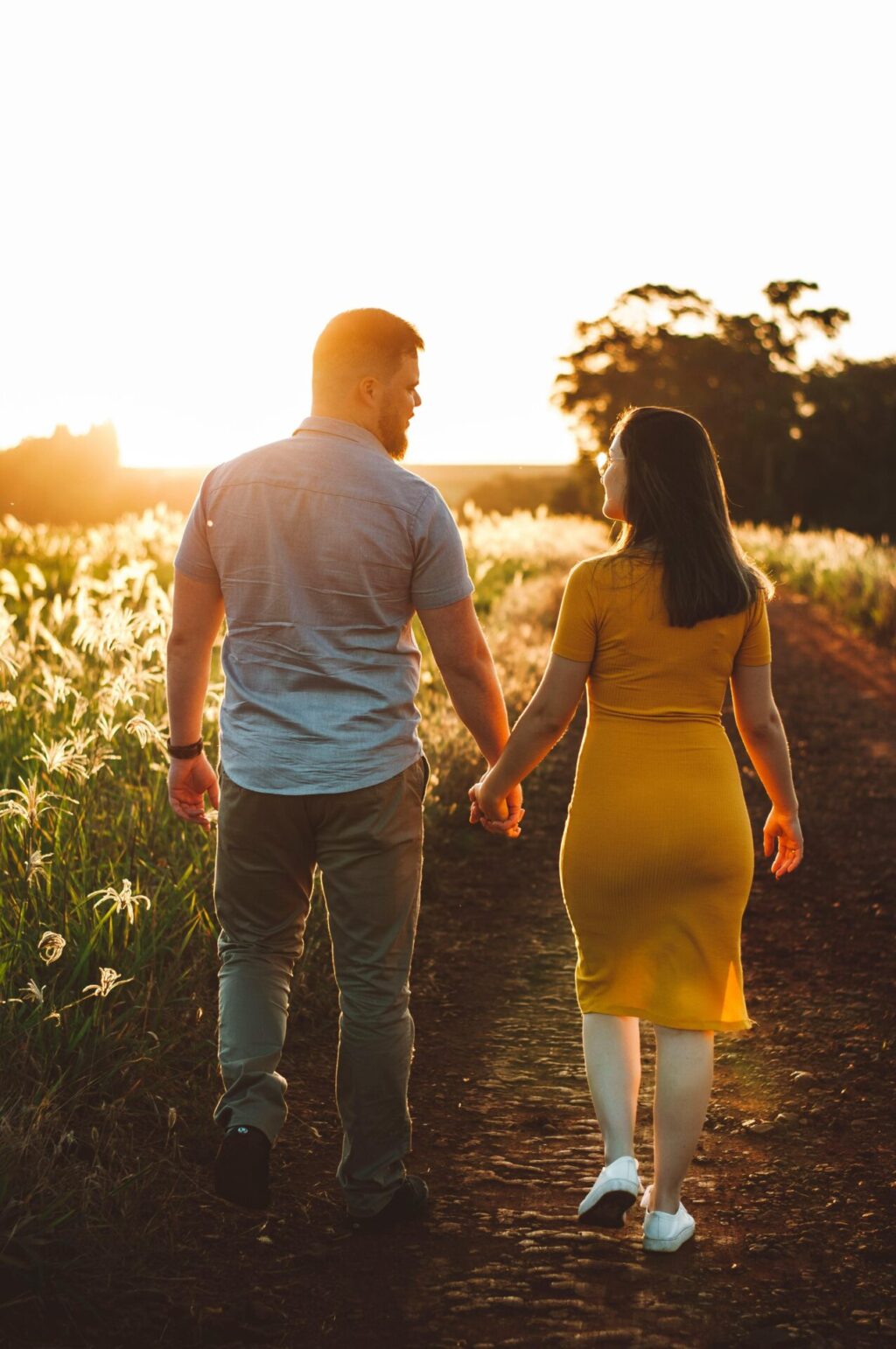 Couple holding hands while walking together through a peaceful countryside landscape, evoking connection, intimacy, and a shared journey in nature.