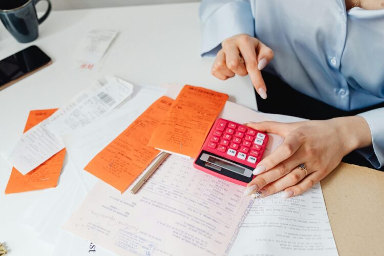 Person holding and using a calculator to manage money.