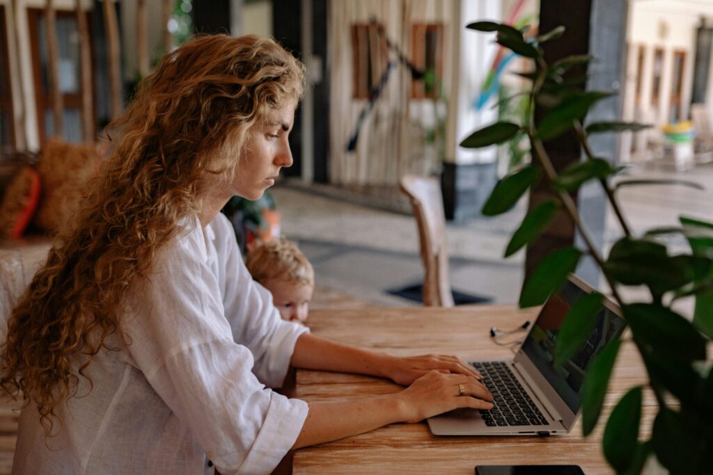 Woman using a laptop at a desk in a bright indoor workspace.
